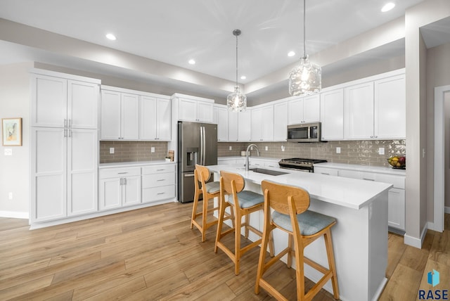 1703 N Otto Ave, Sioux Falls, SD 57110 - kitchen with appliances with stainless steel finishes, a sink, light countertops, a breakfast bar area, and light wood-style floors