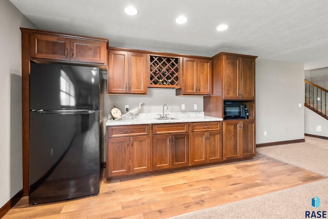 8216 W 51st St, Sioux Falls, SD 57106 - kitchen with black appliances, a sink, brown cabinetry, baseboards, and light wood-style flooring