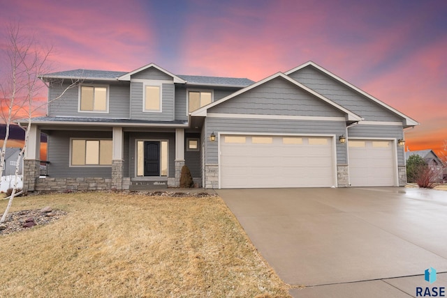 2101 S Meadowview Ave, Sioux Falls, SD 57110 - view of front of house with stone siding, an attached garage, driveway, a front yard, and covered porch
