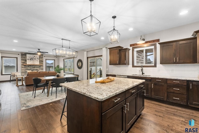2101 S Meadowview Ave, Sioux Falls, SD 57110 - kitchen featuring a sink, dark brown cabinets, dark wood-style floors, backsplash, and a center island
