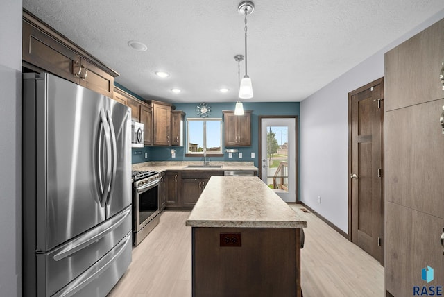 8620 W 22nd St, Sioux Falls, SD 57106 - kitchen with stainless steel appliances, a center island, light countertops, light wood-style flooring, and a textured ceiling