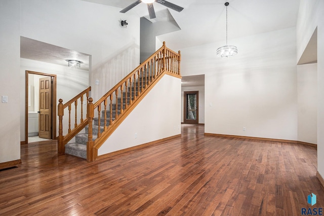 7604 E Palomino Rd, Sioux Falls, SD 57110 - unfurnished living room featuring high vaulted ceiling, wood finished floors, a chandelier, ceiling fan, and stairs