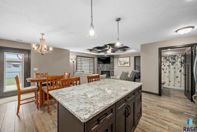 217 E Antioch St, Tea, SD 57064 - kitchen with light wood-type flooring, plenty of natural light, a fireplace, a tray ceiling, and a textured ceiling
