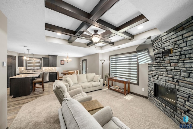 217 E Antioch St, Tea, SD 57064 - living area featuring a stone fireplace, a chandelier, coffered ceiling, beam ceiling, and ceiling fan