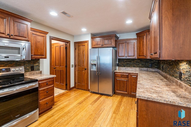 5509 E Eastbridge Pl, Sioux Falls, SD 57110 - kitchen with appliances with stainless steel finishes, light wood-type flooring, backsplash, recessed lighting, and light stone countertops