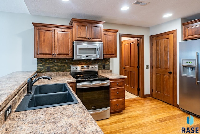 5509 E Eastbridge Pl, Sioux Falls, SD 57110 - kitchen with stainless steel appliances, light wood-type flooring, light countertops, tasteful backsplash, and recessed lighting