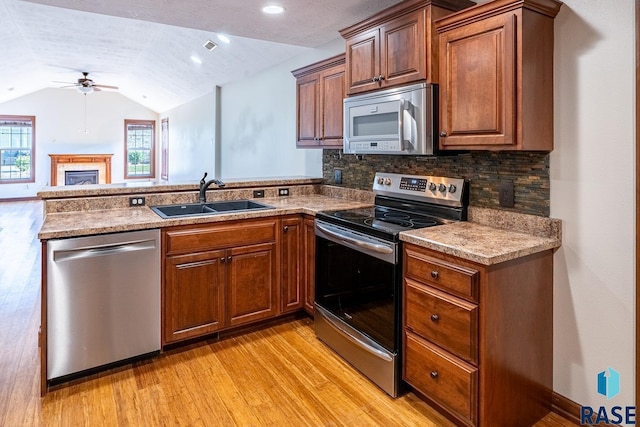 5509 E Eastbridge Pl, Sioux Falls, SD 57110 - kitchen with appliances with stainless steel finishes, ceiling fan, a peninsula, light wood finished floors, and vaulted ceiling