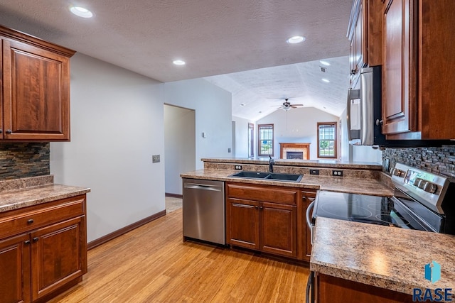 5509 E Eastbridge Pl, Sioux Falls, SD 57110 - kitchen featuring stainless steel appliances, a fireplace, light wood finished floors, a ceiling fan, and vaulted ceiling