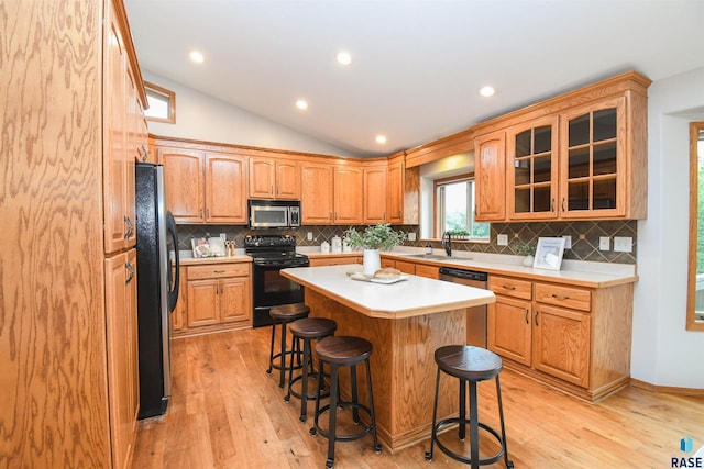 6312 S Heatherridge Ave, Sioux Falls, SD 57108 - kitchen with appliances with stainless steel finishes, a kitchen bar, light countertops, light wood-style floors, and glass insert cabinets