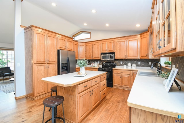 6312 S Heatherridge Ave, Sioux Falls, SD 57108 - kitchen with stainless steel appliances, vaulted ceiling, light countertops, light wood-style floors, and a kitchen island