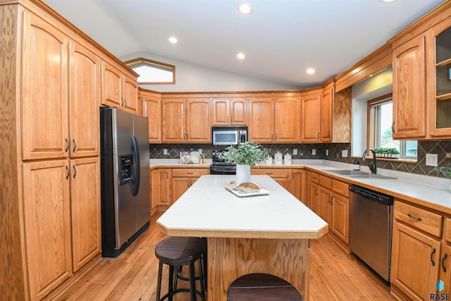 6312 S Heatherridge Ave, Sioux Falls, SD 57108 - kitchen featuring stainless steel appliances, vaulted ceiling, light wood finished floors, a kitchen bar, and light countertops