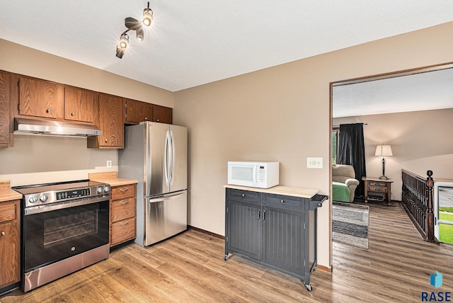 5909 W Bakker Park Dr, Sioux Falls, SD 57106 - kitchen featuring stainless steel appliances, under cabinet range hood, light countertops, light wood-style floors, and brown cabinets
