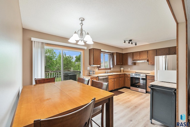 5909 W Bakker Park Dr, Sioux Falls, SD 57106 - kitchen featuring appliances with stainless steel finishes, a chandelier, light countertops, light wood-style flooring, and under cabinet range hood