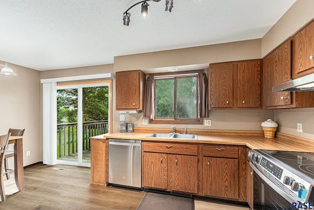 5909 W Bakker Park Dr, Sioux Falls, SD 57106 - kitchen with appliances with stainless steel finishes, light countertops, light wood-style flooring, brown cabinetry, and a textured ceiling