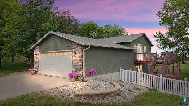 26481 487th Ave, Valley Springs, SD 57068 - property exterior at dusk featuring a garage, a wooden deck, driveway, stairs, and stone siding