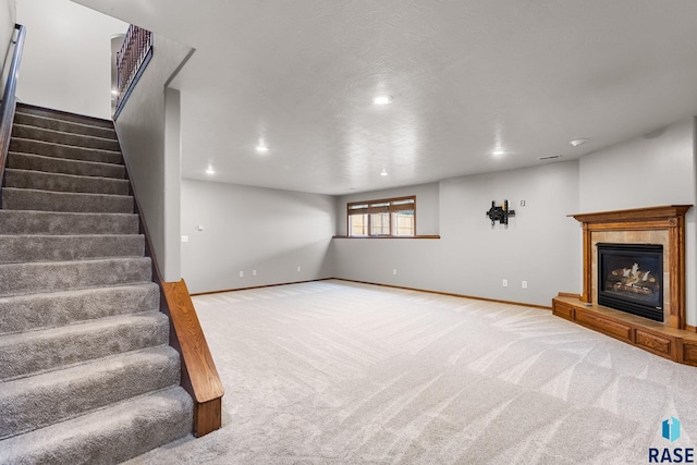 908 W 4th Ave, Lennox, SD 57039 - unfurnished living room featuring carpet flooring, stairway, a glass covered fireplace, and recessed lighting
