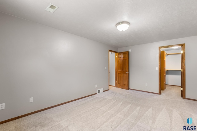 908 W 4th Ave, Lennox, SD 57039 - unfurnished bedroom with a walk in closet, light carpet, a textured ceiling, and a closet