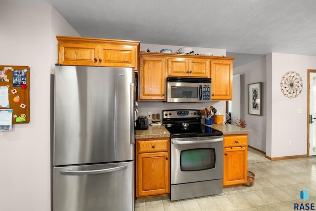 1905 S Wheatland Ct, Sioux Falls, SD 57106 - kitchen featuring stainless steel appliances, brown cabinets, a textured ceiling, and light tile patterned floors