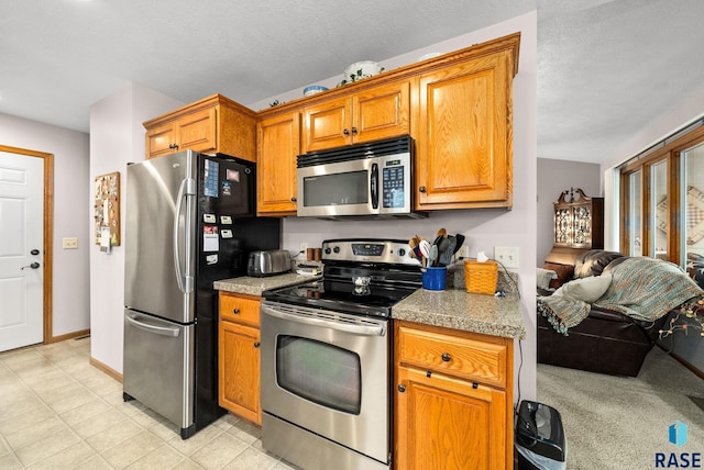 1905 S Wheatland Ct, Sioux Falls, SD 57106 - kitchen featuring stainless steel appliances, brown cabinetry, open floor plan, and light tile patterned flooring