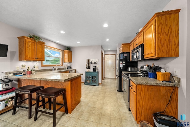 1905 S Wheatland Ct, Sioux Falls, SD 57106 - kitchen with appliances with stainless steel finishes, a peninsula, brown cabinets, recessed lighting, and a kitchen breakfast bar