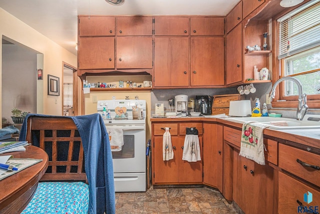 508 E Crawford St, Luverne, MN 56156 - kitchen with open shelves, electric range, light countertops, stone finish floors, and brown cabinetry