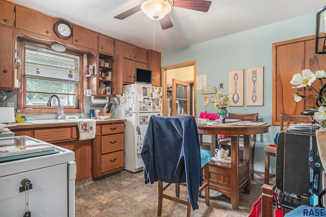 508 E Crawford St, Luverne, MN 56156 - kitchen featuring freestanding refrigerator, brown cabinetry, range, and ceiling fan