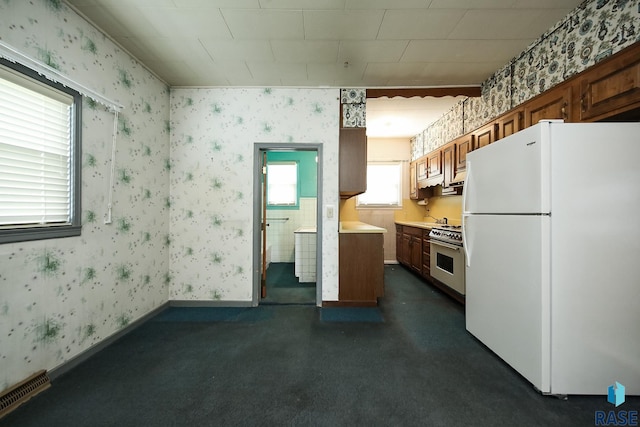 228 N Broadway St, Canton, SD 57013 - kitchen with freestanding refrigerator, high end stainless steel range, brown cabinets, light countertops, and wallpapered walls