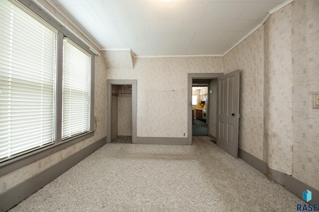 228 N Broadway St, Canton, SD 57013 - unfurnished bedroom featuring multiple windows, crown molding, wallpapered walls, carpet flooring, and a closet