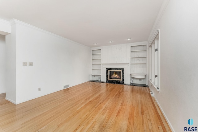 915 E Ridge Rd, Sioux Falls, SD 57105 - unfurnished living room with light wood-style flooring, built in features, a premium fireplace, and crown molding
