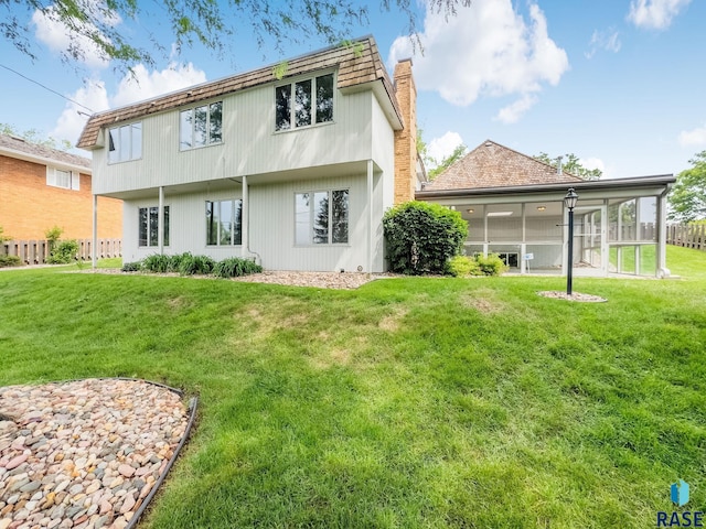 915 E Ridge Rd, Sioux Falls, SD 57105 - back of house with a chimney, a lawn, and a sunroom