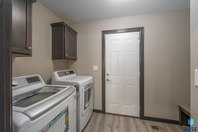 7513 E 49th St, Sioux Falls, SD 57110 - washroom featuring washing machine and clothes dryer, cabinet space, and light wood-style floors