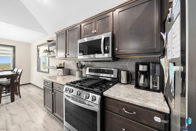 7513 E 49th St, Sioux Falls, SD 57110 - kitchen with stainless steel appliances, lofted ceiling, dark brown cabinetry, decorative backsplash, and light wood-style flooring