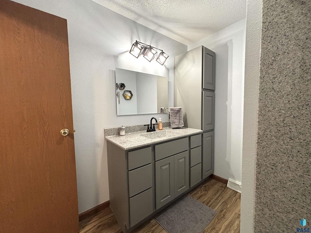 421 E 2nd St, Miller, SD 57362 - bathroom with wood finished floors, vanity, and a textured ceiling