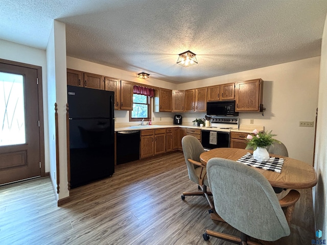 421 E 2nd St, Miller, SD 57362 - kitchen featuring black appliances, light countertops, wood finished floors, a textured ceiling, and brown cabinets