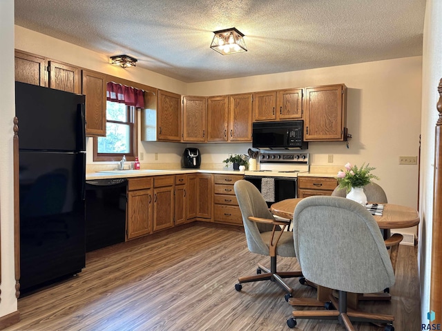 421 E 2nd St, Miller, SD 57362 - kitchen featuring black appliances, wood finished floors, brown cabinetry, light countertops, and a textured ceiling