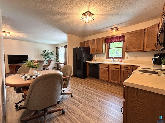 421 E 2nd St, Miller, SD 57362 - kitchen featuring black appliances, a textured ceiling, light countertops, brown cabinets, and light wood-style flooring