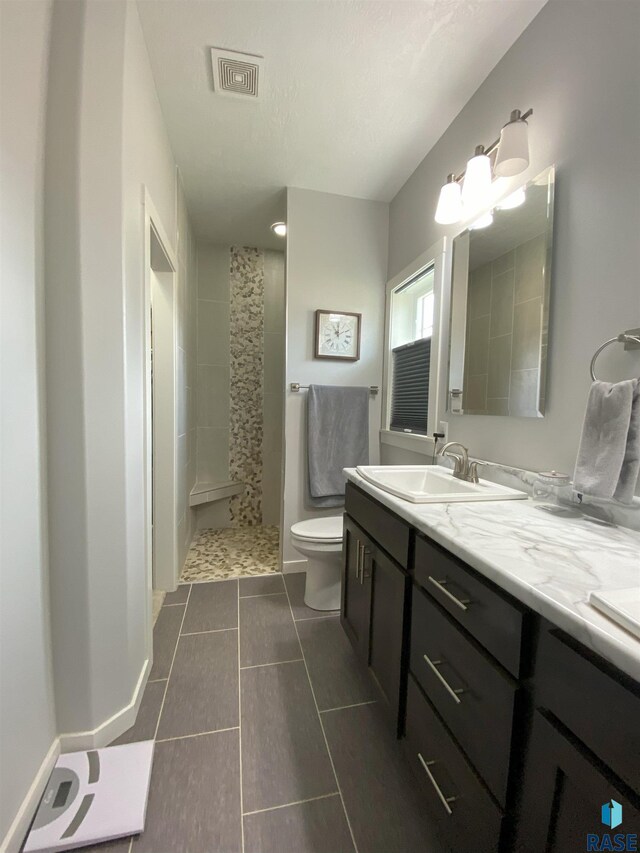 8617 W Bryggen Ct, Sioux Falls, SD 57107 - bathroom with tiled shower, double vanity, and tile patterned flooring
