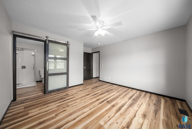 301 W 6th St, Crooks, SD 57020 - unfurnished bedroom featuring a barn door, wood finished floors, and a ceiling fan