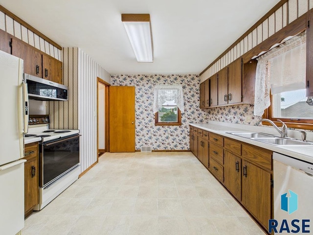 1721 W 11th St, Sioux Falls, SD 57104 - kitchen featuring white appliances, wallpapered walls, light countertops, brown cabinetry, and plenty of natural light