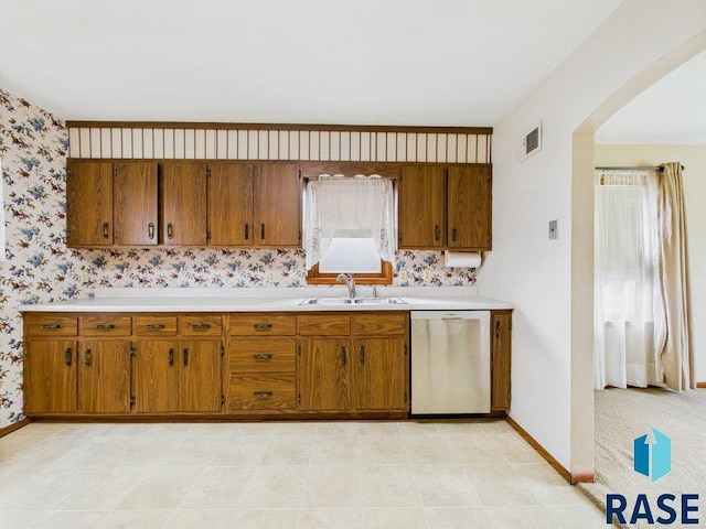 1721 W 11th St, Sioux Falls, SD 57104 - kitchen with dishwasher, brown cabinetry, arched walkways, light countertops, and wallpapered walls