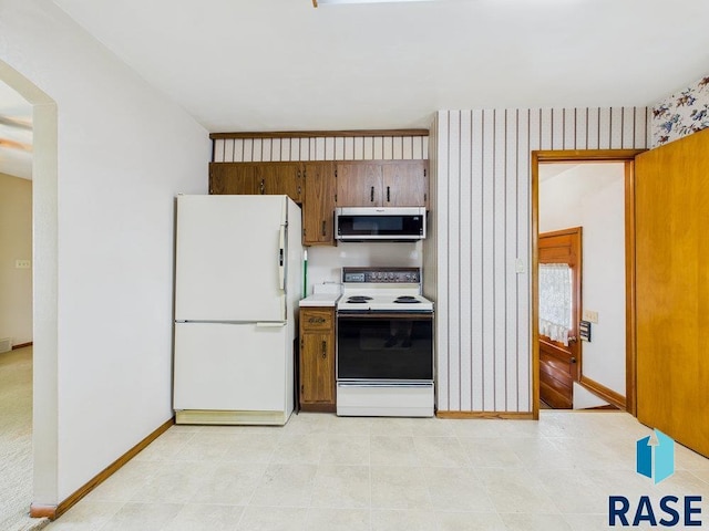 1721 W 11th St, Sioux Falls, SD 57104 - kitchen with white appliances, brown cabinetry, light countertops, and arched walkways