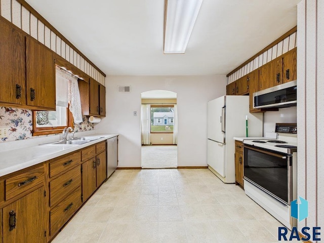 1721 W 11th St, Sioux Falls, SD 57104 - kitchen featuring stainless steel appliances, arched walkways, light countertops, and brown cabinetry