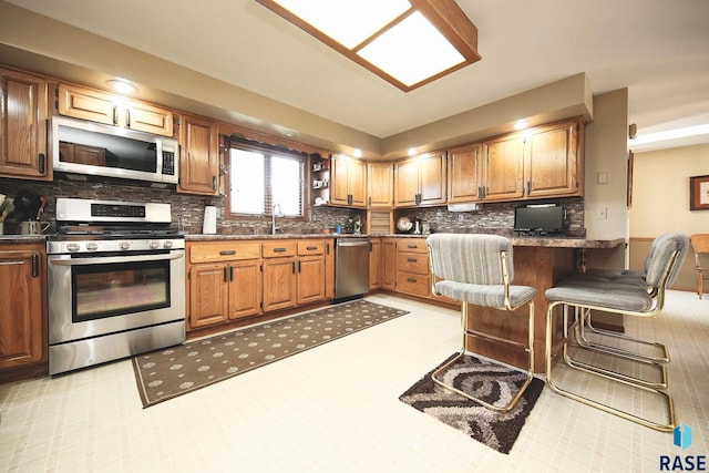429 S Elm St, Lennox, SD 57039 - kitchen with stainless steel appliances, decorative backsplash, dark countertops, a peninsula, and a kitchen bar