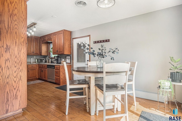 300 W 3rd St, Tea, SD 57064 - kitchen featuring stainless steel dishwasher, brown cabinets, light wood finished floors, and light countertops