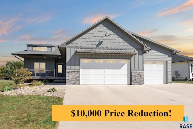 116 Lynx St, Valley Springs, SD 57068 - view of front of home with board and batten siding, a garage, driveway, and stone siding
