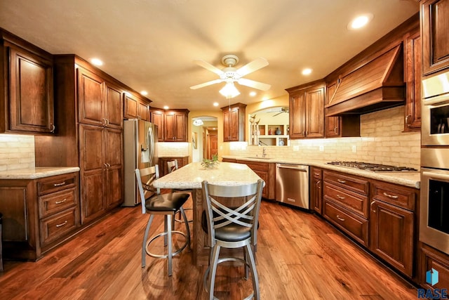 6811 E Split Rock Cir, Sioux Falls, SD 57110 - kitchen with stainless steel appliances, ceiling fan, a kitchen island, tasteful backsplash, and a breakfast bar