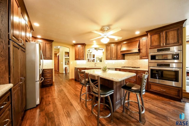 6811 E Split Rock Cir, Sioux Falls, SD 57110 - kitchen featuring stainless steel appliances, arched walkways, a ceiling fan, custom exhaust hood, and tasteful backsplash