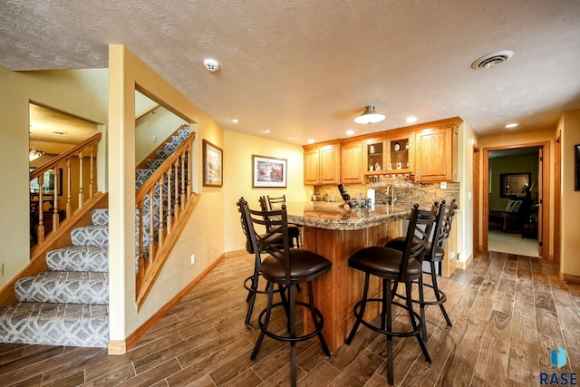 6811 E Split Rock Cir, Sioux Falls, SD 57110 - indoor wet bar featuring wood finish floors, stairs, recessed lighting, a textured ceiling, and decorative backsplash