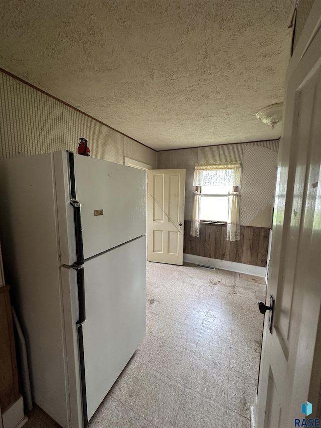 613 N Cedar St, Luverne, MN 56156 - kitchen featuring freestanding refrigerator, tile patterned floors, a textured ceiling, and wood walls