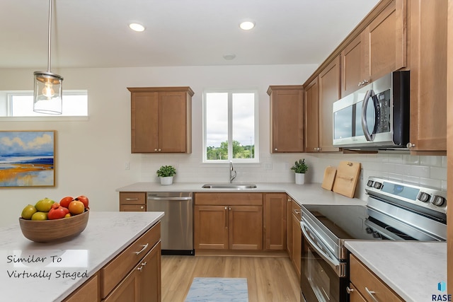 333 S Willow Spring Dr, Sioux Falls, SD 57110 - kitchen featuring stainless steel appliances, brown cabinetry, light wood-style floors, backsplash, and recessed lighting
